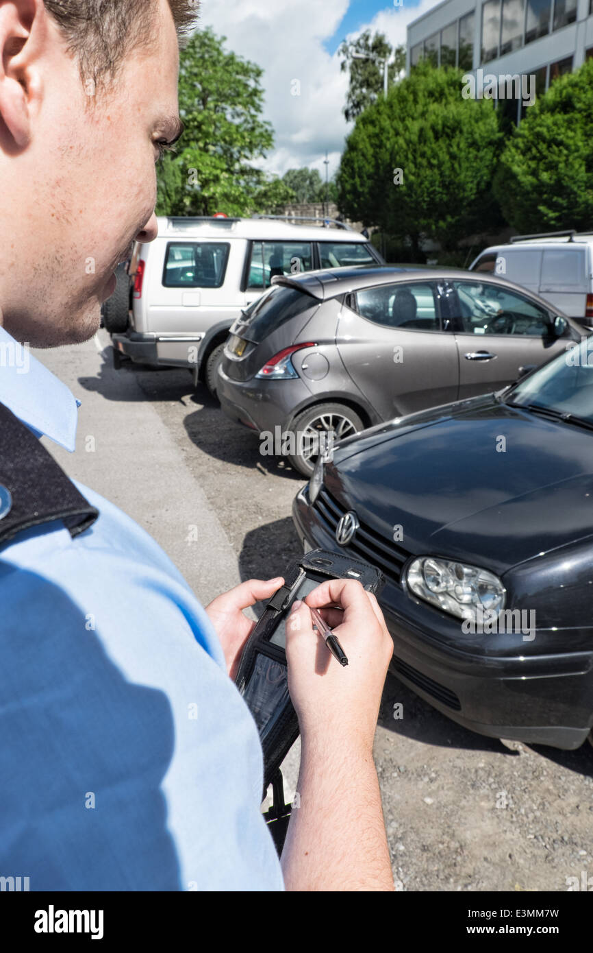 Conseil d'un agent d'application de stationnement en tenant les détails de voitures stationnées dans un parking Banque D'Images