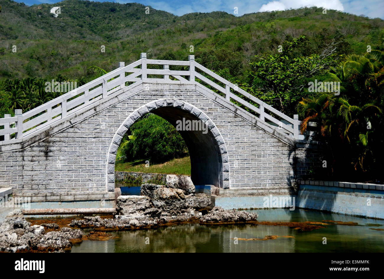San Ya, Chine : un pont en pierre avec un arc haut enjambe un cours d'eau dans les jardins tropicaux à la Temple de Nanshan Sanya Banque D'Images