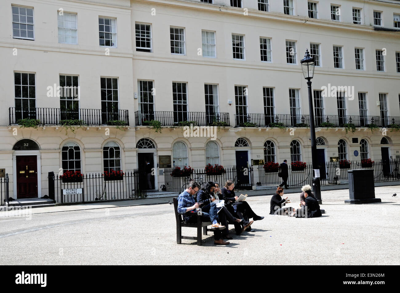 Les gens assis sur un banc de manger le déjeuner à Fitzroy Square, Bloomsbury Londres Angleterre Royaume-uni Banque D'Images