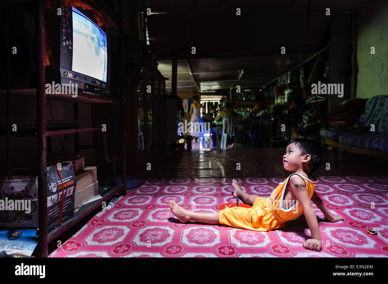 Garçon à regarder la télévision dans une maison longue, Bornéo, Malaisie. Banque D'Images