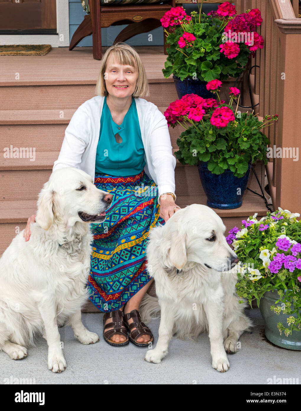 Femme qui pose pour la photo de porche avec deux chiens Golden Retriever de couleur platine Banque D'Images