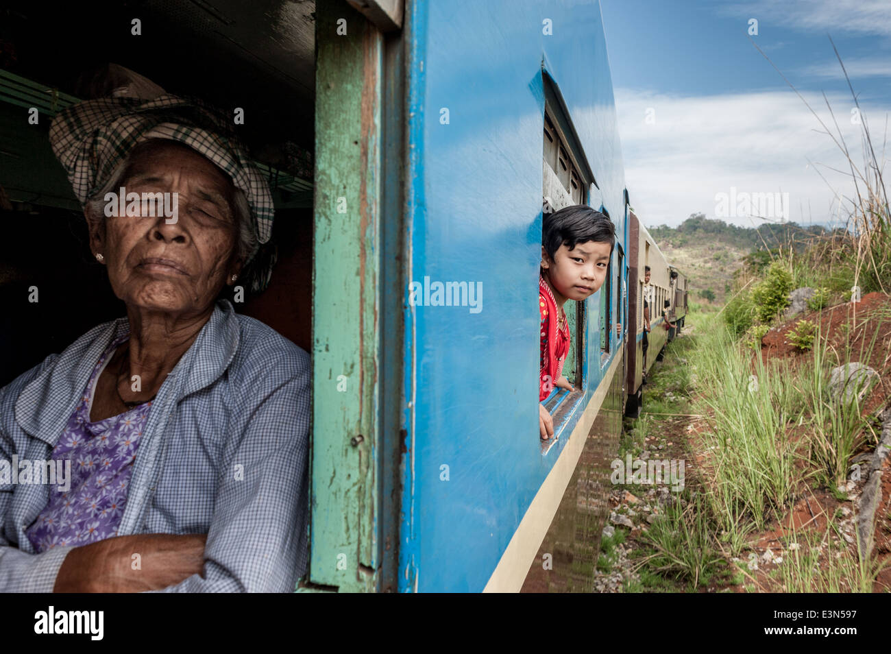 Fille en regardant par la fenêtre d'un train lent et vieille femme dormir, le Myanmar, l'Asie Banque D'Images