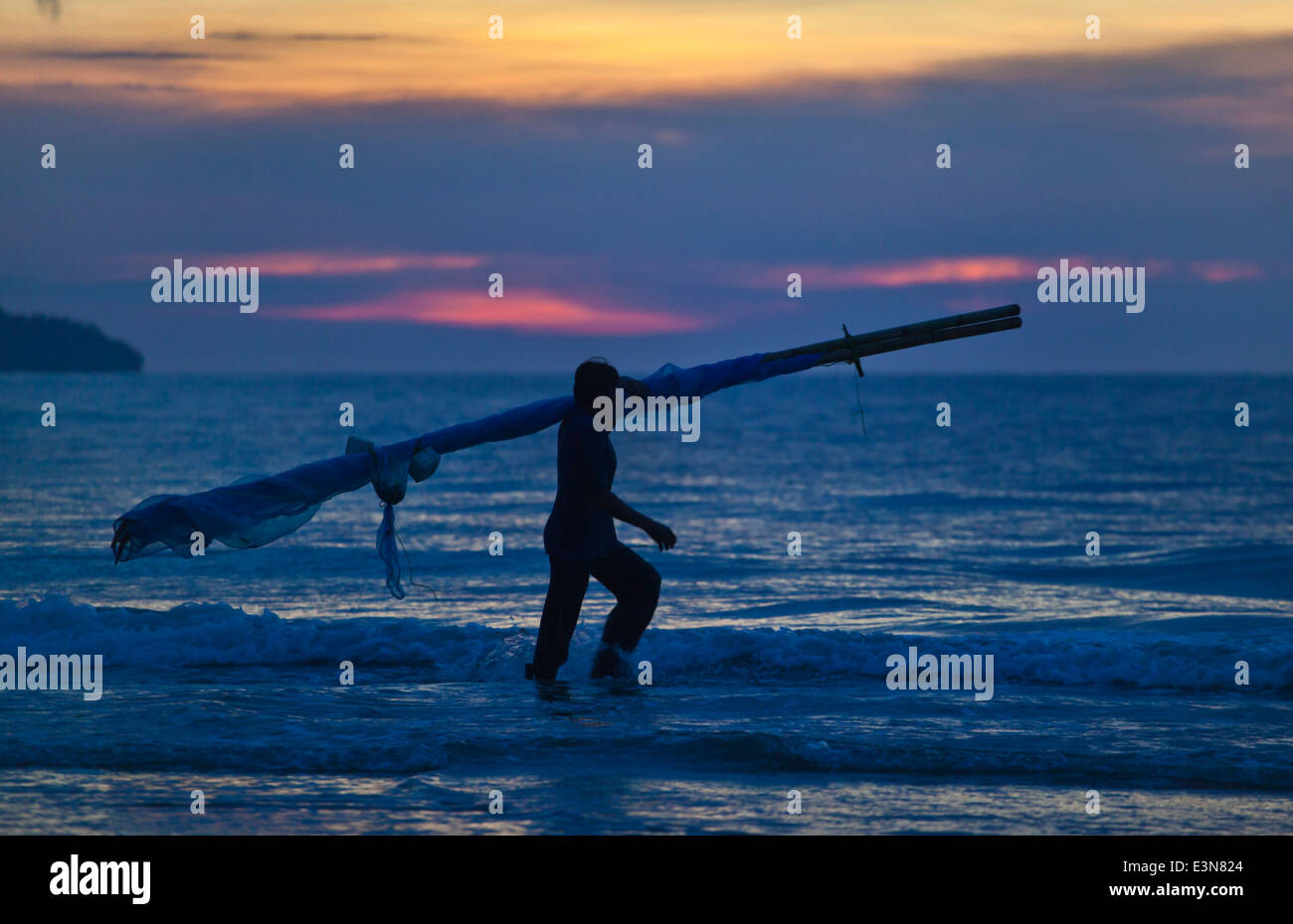 Un pêcheur patauge dans la mer pour définir ses filets de pêche - la mer d'Andaman, Thaïlande Banque D'Images