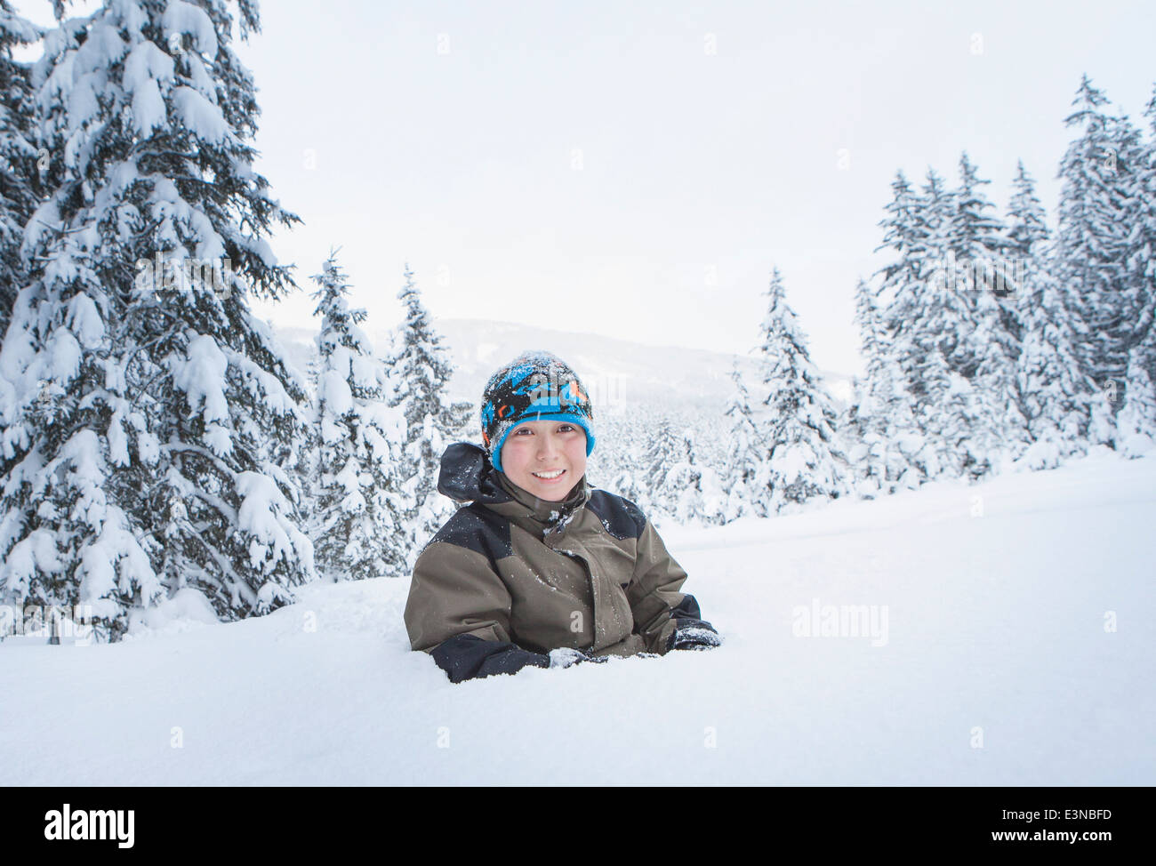 Portrait of smiling boy enterré dans la neige Banque D'Images