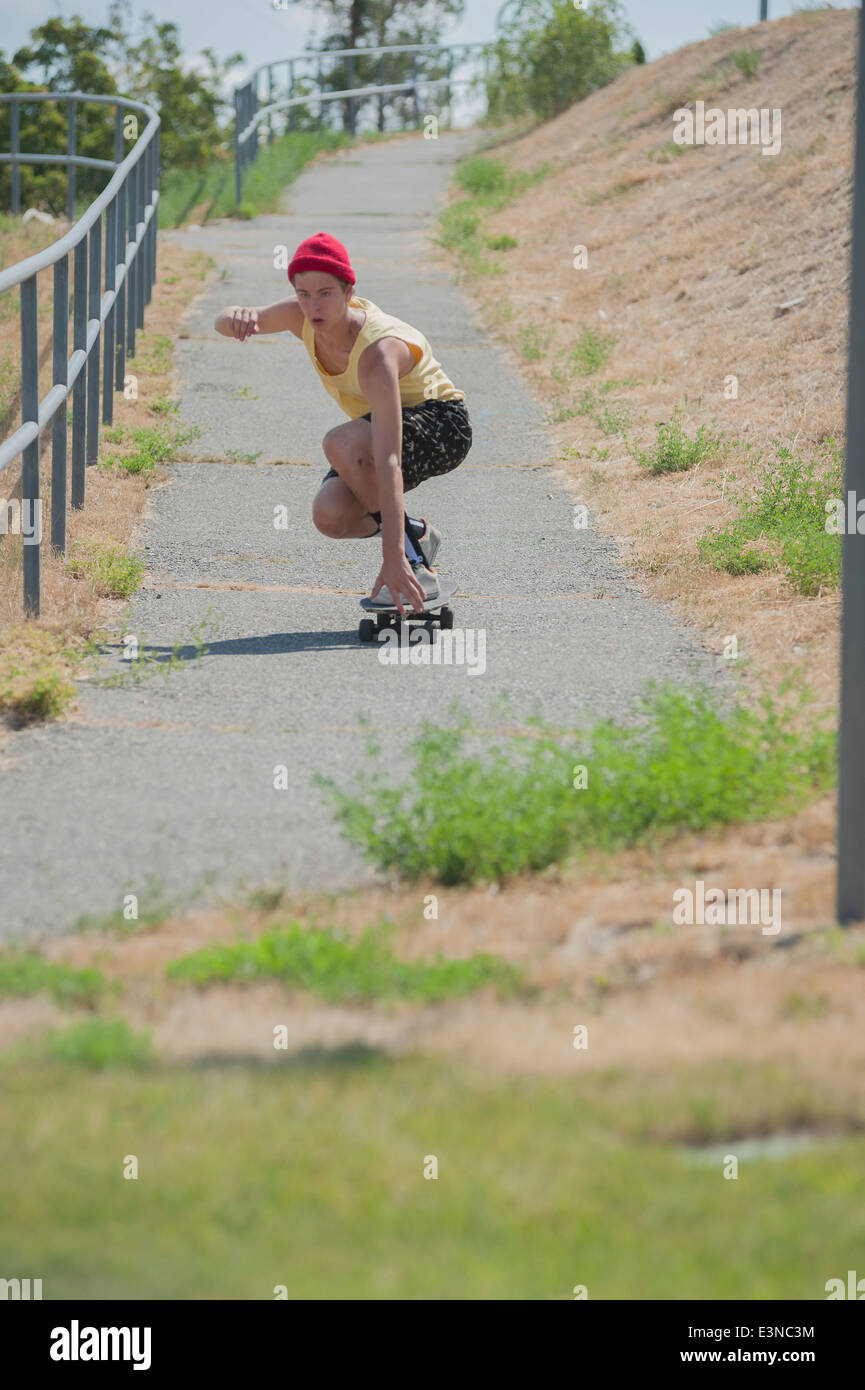 La longueur totale de l'homme skateboarding sur sentier Banque D'Images