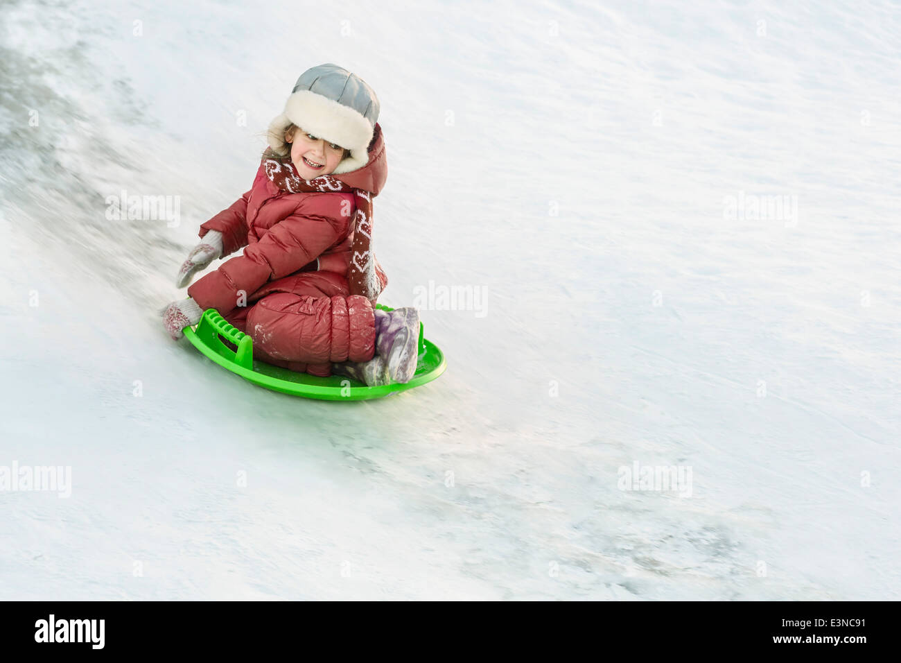 Toute la longueur de happy girl la luge dans la neige Banque D'Images