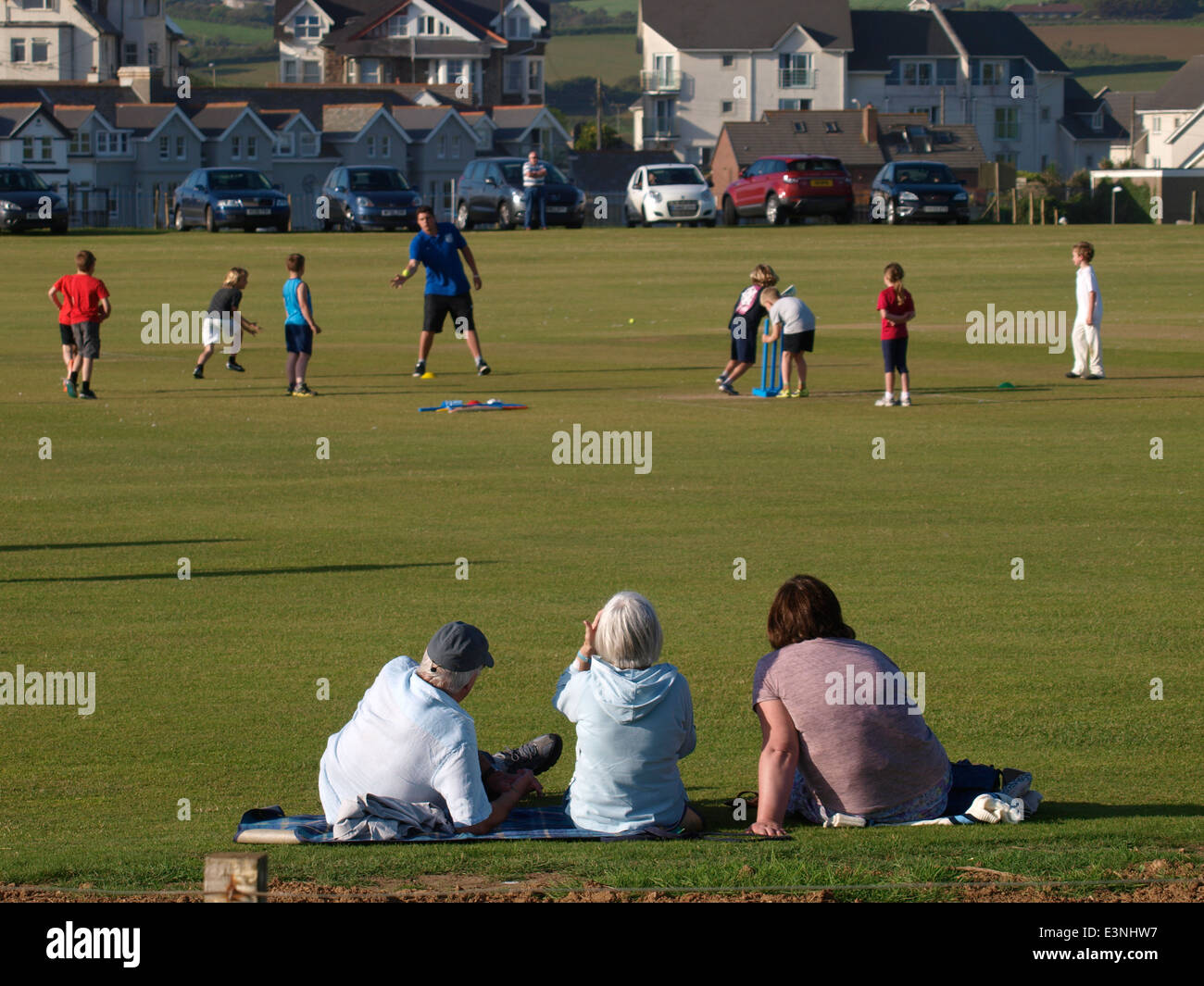 Mère et grands-parents à regarder les enfants à apprendre à jouer au cricket, Bude, Cornwall, UK Banque D'Images