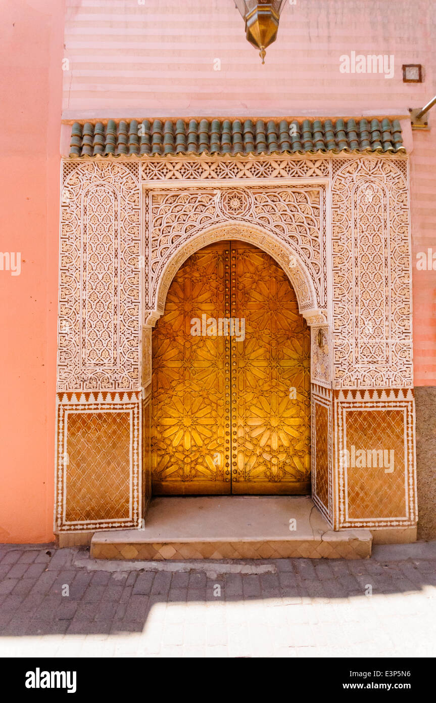 Double portes d'or avec un plâtre ouvragé ajouré arch à Marrakech, Maroc Banque D'Images