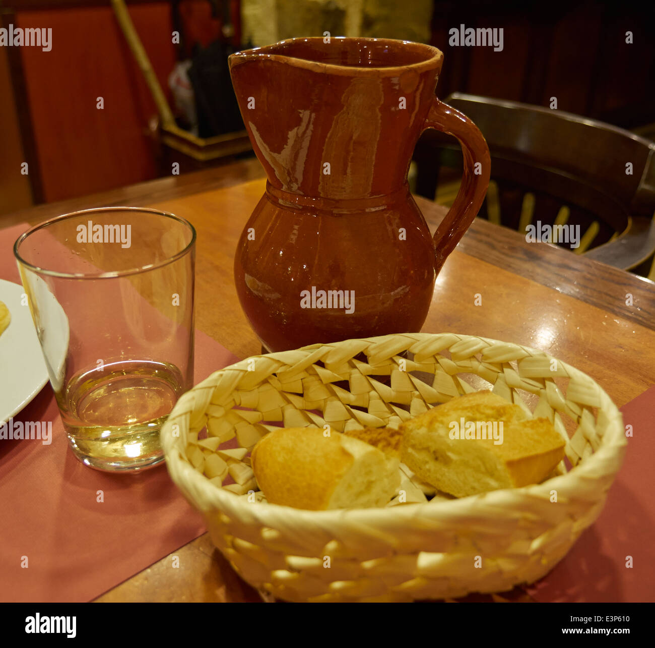 Un pichet de vin blanc avec une corbeille de pain frais servi dans un restaurant rustique en Espagne Banque D'Images