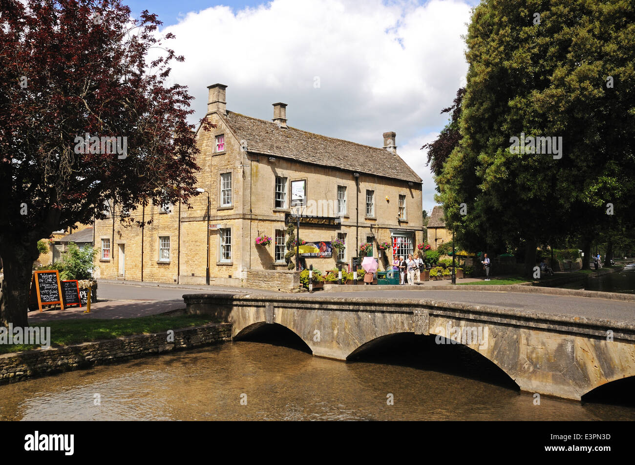 Passerelle en pierre de l'autre côté de la rivière Windrush avec l'Kingsbridge Inn à l'arrière, Bourton On The Water, England, UK. Banque D'Images