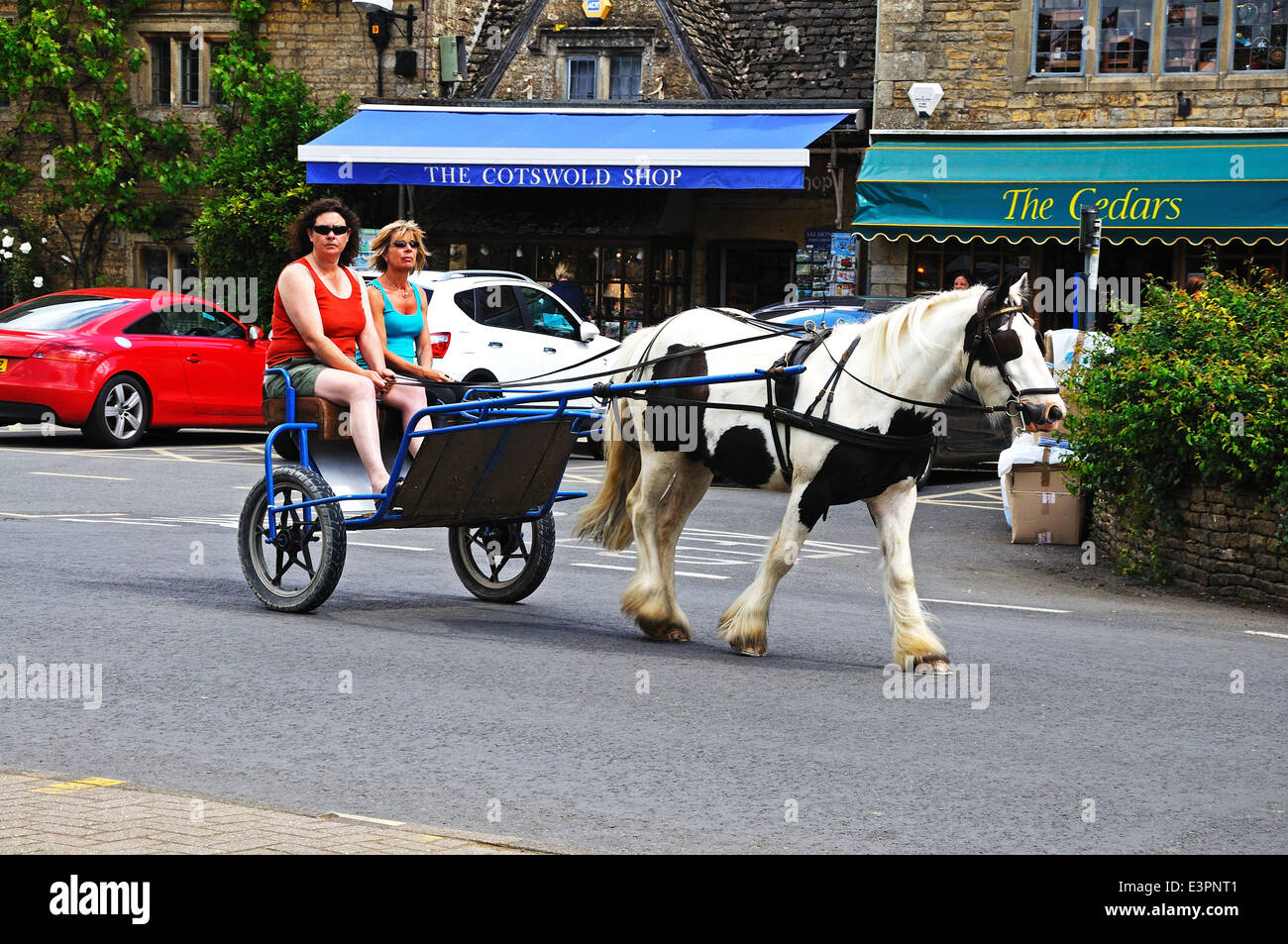 Les touristes de prendre un tour dans un piège et à cheval autour du village, Bourton On The Water, England, UK. Banque D'Images