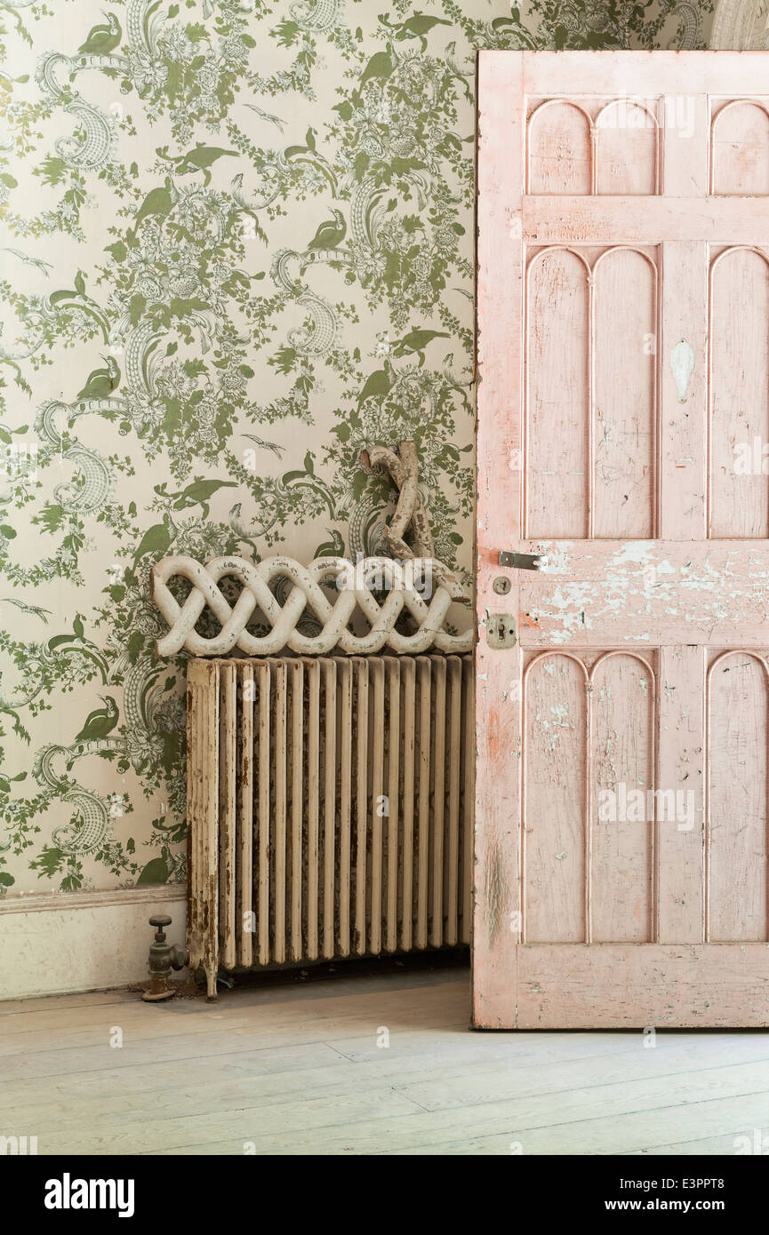 Morceau de casse de récupération architecturale sur l'ancien radiateur par porte ouverte avec l'écaillage de la peinture. Banque D'Images