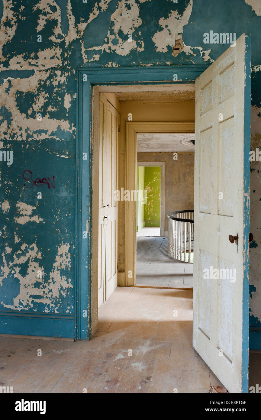 Dans la chambre avec la porte ouverte et à l'écaillement de la peinture mur fissuré Banque D'Images