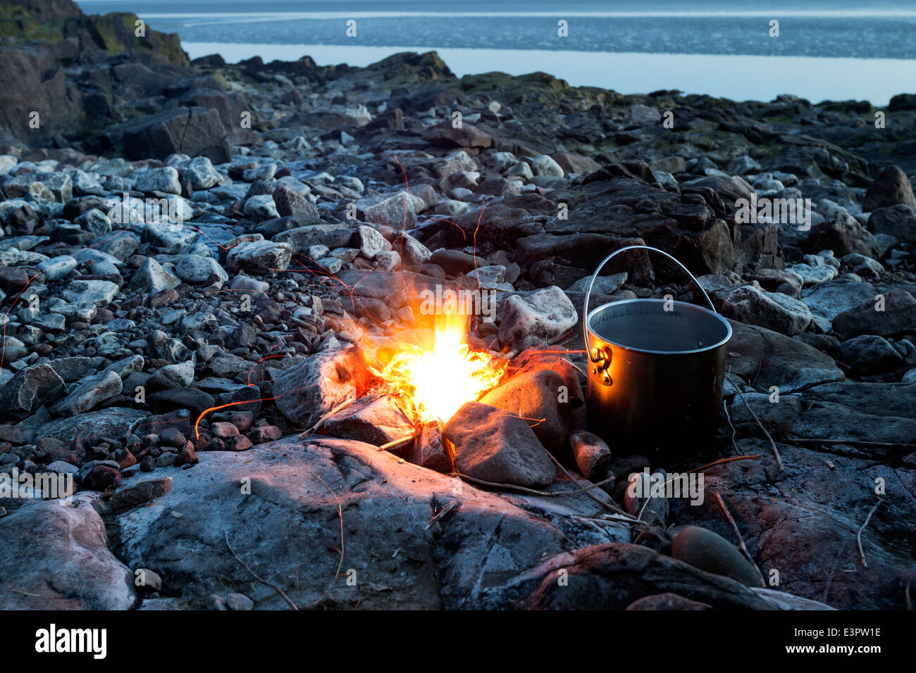 Avec Marmite du feu sur une plage de rochers au crépuscule England UK Banque D'Images