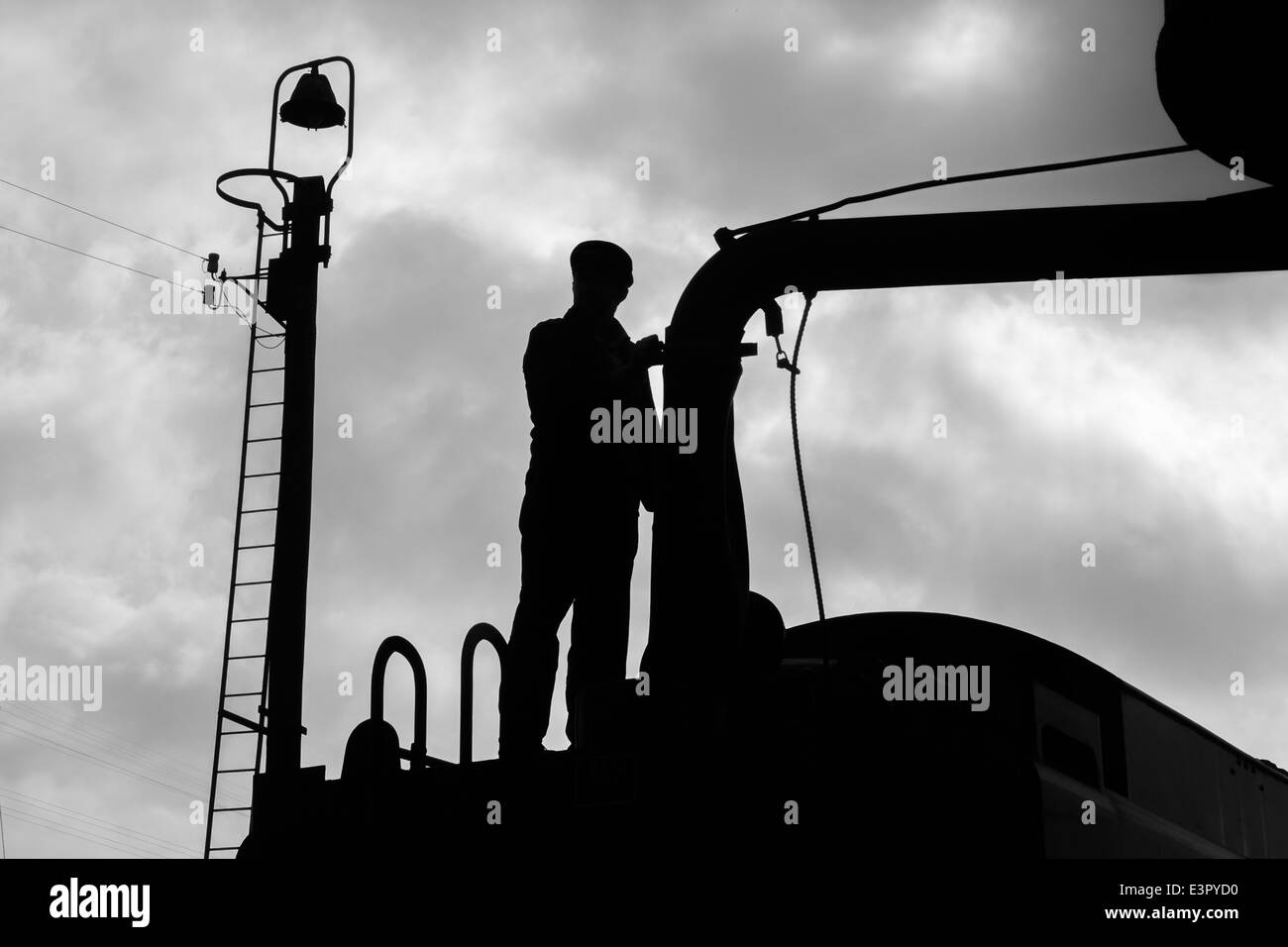 Le pompier d'un train à vapeur du remplissage avec de l'eau. Banque D'Images