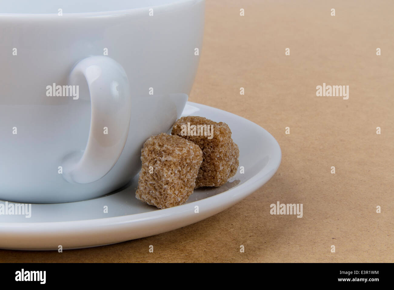 Couper grossièrement les cubes de sucre de canne blanc avec une tasse à café et soucoupe Banque D'Images