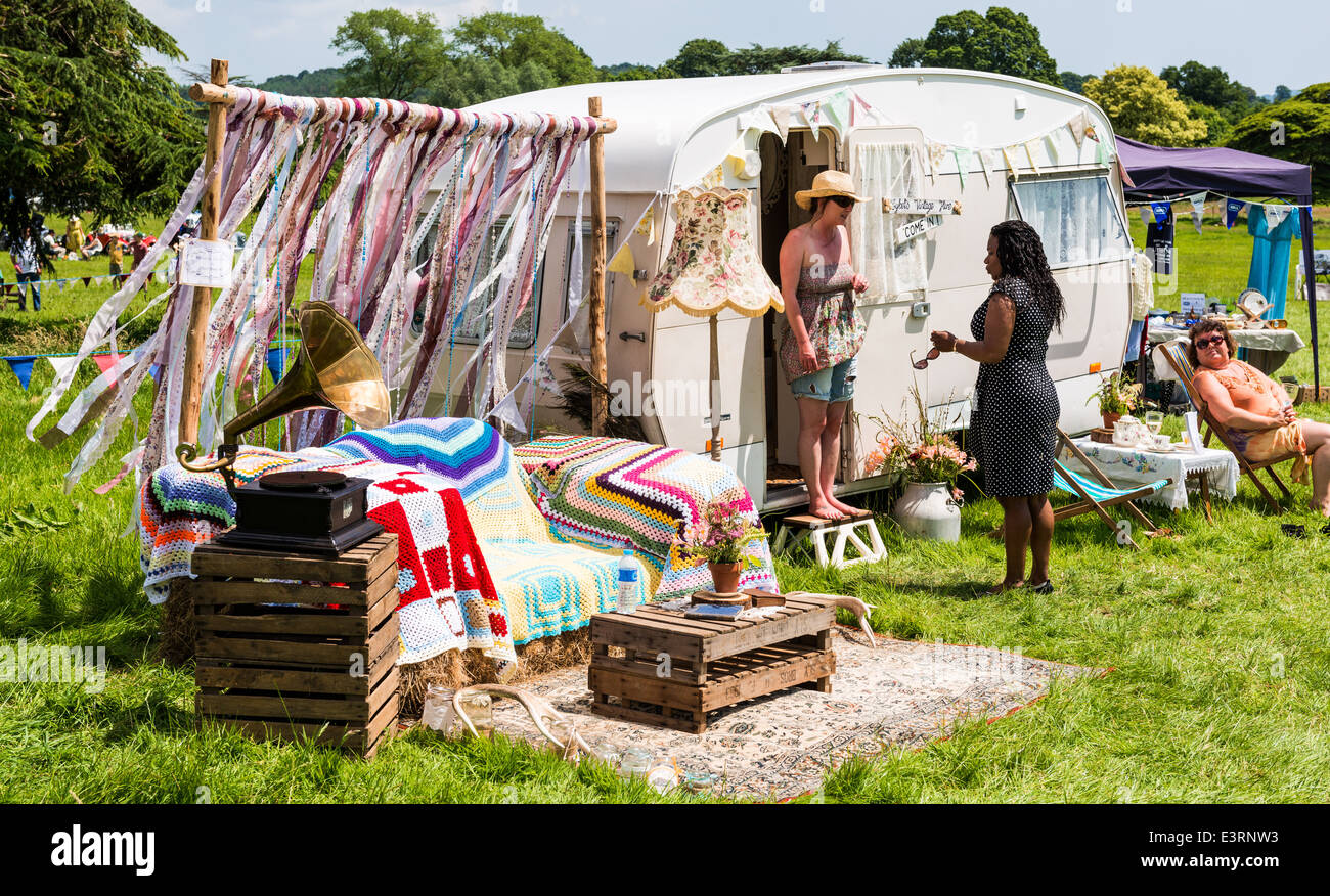 L'est du Devon, Angleterre. Une femme assise sur une chaise devant sa vieille caravane vintage à une fête dans une maison de campagne. Banque D'Images