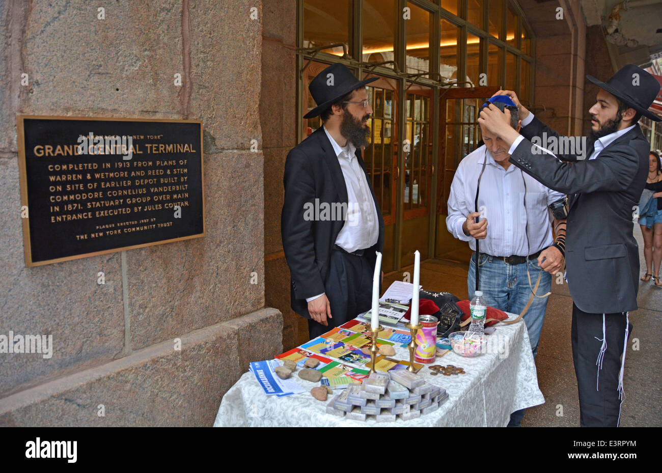 Les Juifs hassidiques Loubavitch encourager un passant pour mettre sur phylactères et dire une prière. L'extérieur de la gare Grand Central à New York Banque D'Images