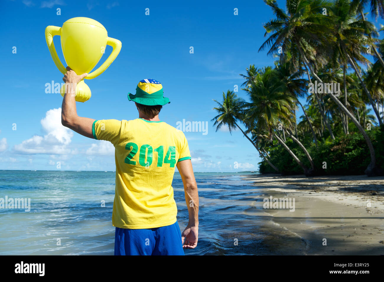 Joueur de football brésilien en 2014 shirt Brésil couleurs holding trophy jusqu'à la plage de Nordeste Bahia Banque D'Images