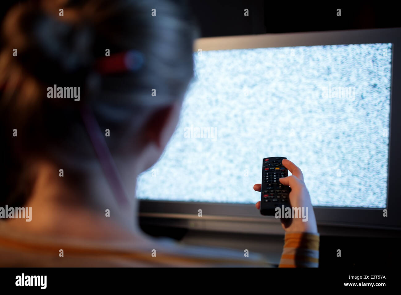 Woman with remote control à l'avant du téléviseur Banque D'Images