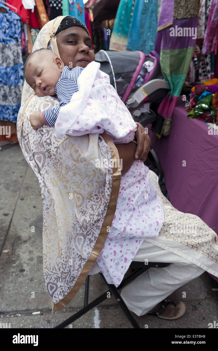 Grand-mère est titulaire d'un petit-enfant du nourrisson à foire de rue dans 'Little Bangladesh' dans la section de Kensington Brooklyn, NY, 2014. Banque D'Images