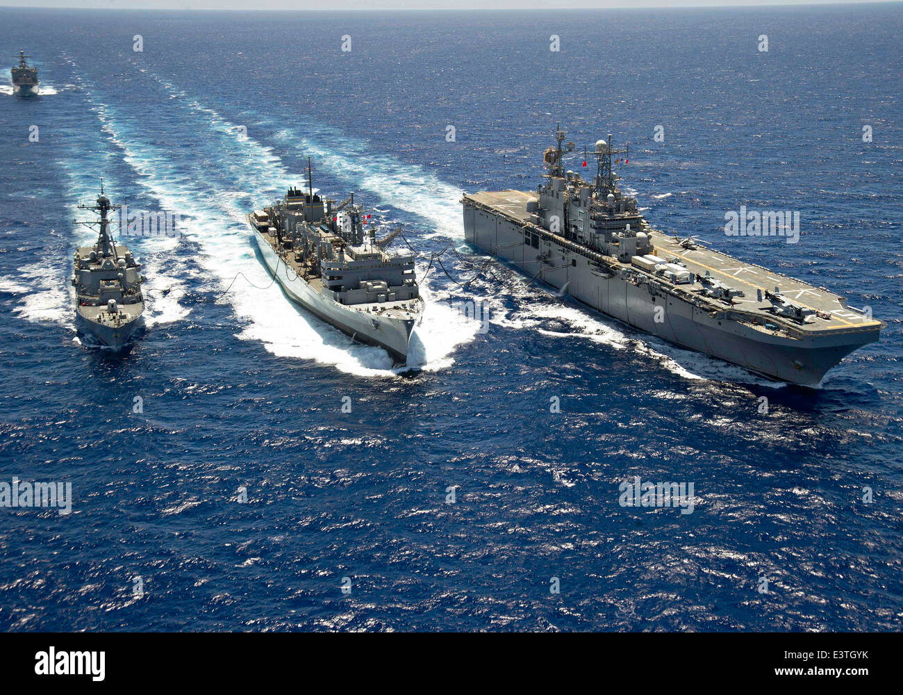 Navire d'assaut amphibie de la Marine américaine USS Peleliu et classe Arleigh Burke destroyer lance-missiles USS Spruance au cours d'un ravitaillement en mer avec le transport maritime militaire rapide Commande de navire de combat l'USNS Rainier pendant des exercices RIMPAC 24 juin 2014 au large de la côte d'Hawaï. Banque D'Images