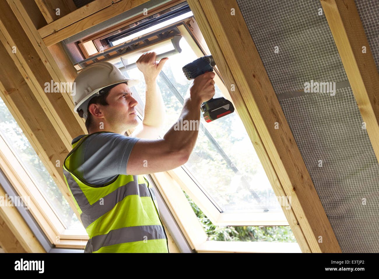 Travailleur de la construction en utilisant la mèche à poser la vitre Banque D'Images