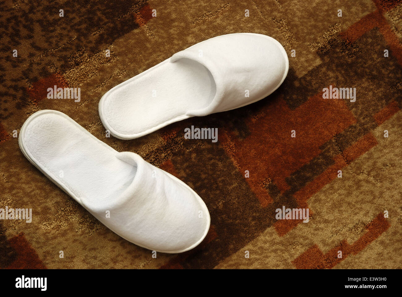 Paire de chaussons blancs sur un tapis Banque D'Images