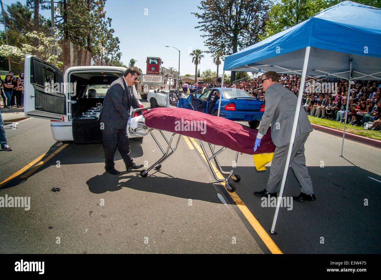 Des bénévoles locaux undertakers recueillir le 'Corpse' de la victime d'un accident dans une dramatisation pour des élèves du secondaire sur les dangers de l'alcool au volant à Anaheim, CA. Remarque foule en arrière-plan. Banque D'Images