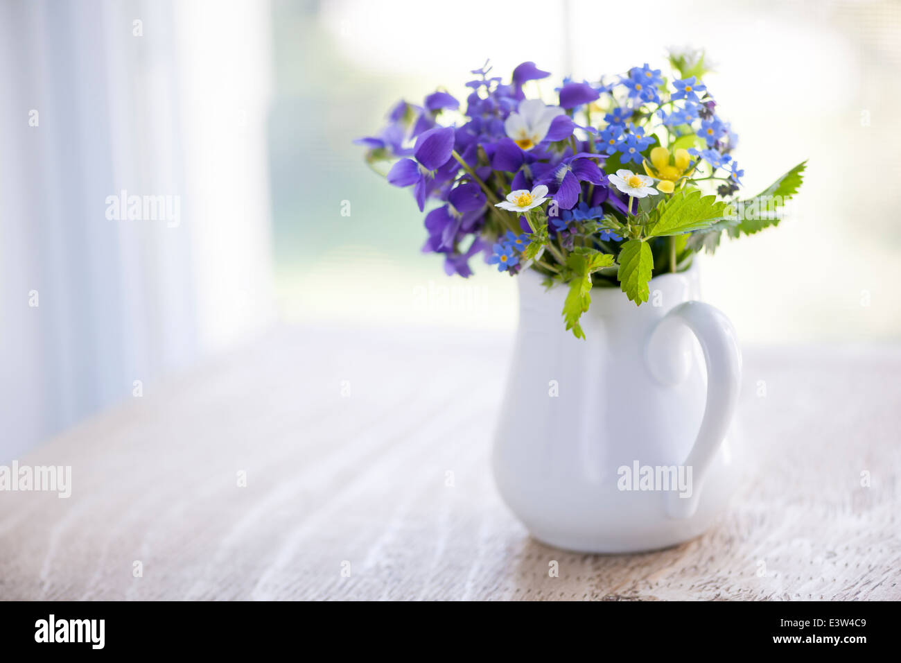 Bouquet de fleurs sauvages en vase blanc sur la table en bois rustique près de fenêtre avec copie espace, lumière naturelle Banque D'Images