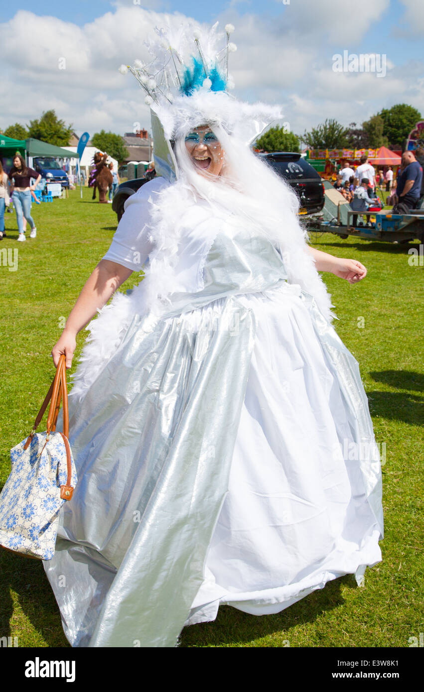 Une femme vêtue comme une bonne fée en robe de satin blanc virevoltant et rire à huis clos à Denbigh ville carnaval d'été Banque D'Images