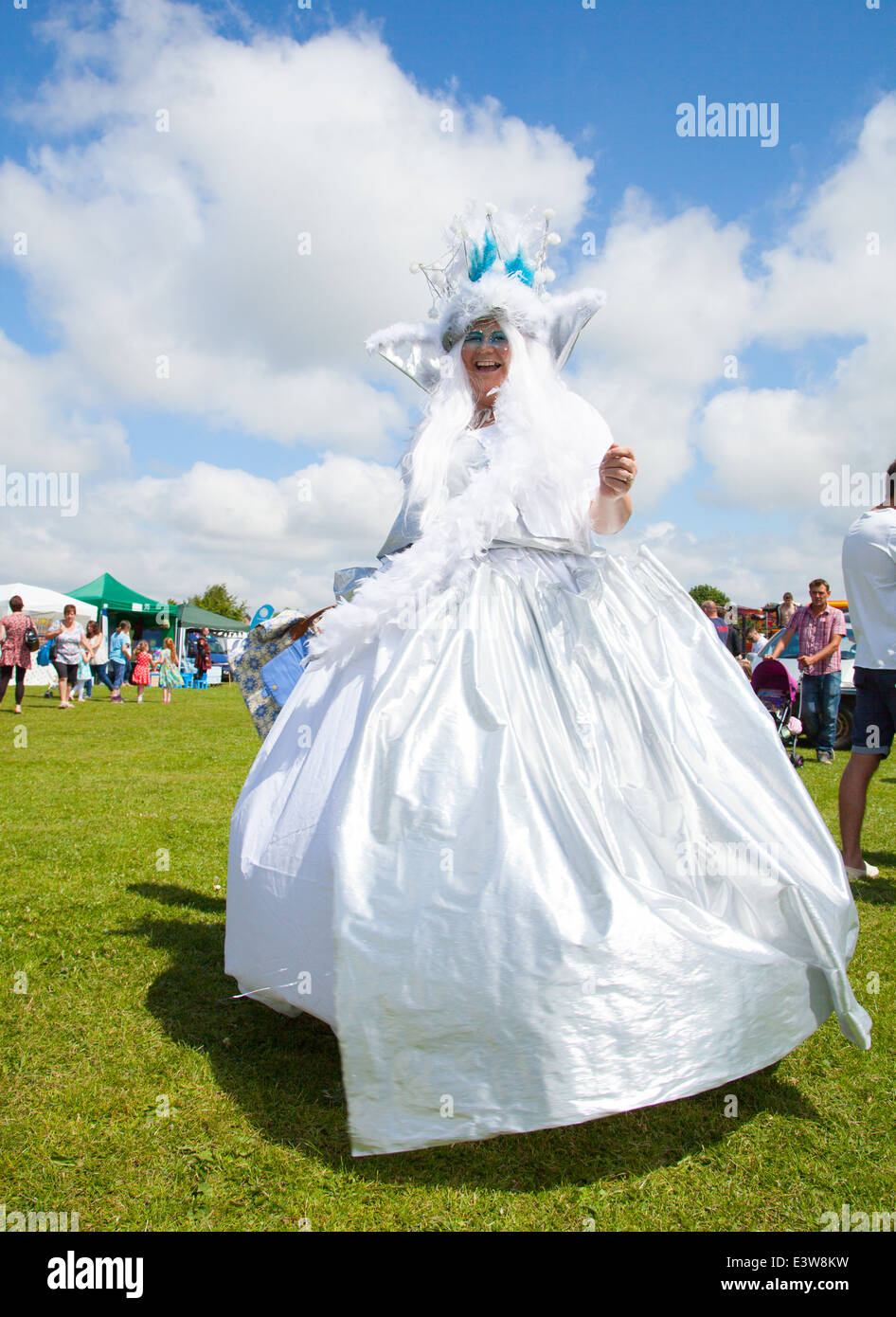 Une femme vêtue comme une bonne fée en robe de satin blanc virevoltant et rire à huis clos à Denbigh ville carnaval d'été Banque D'Images