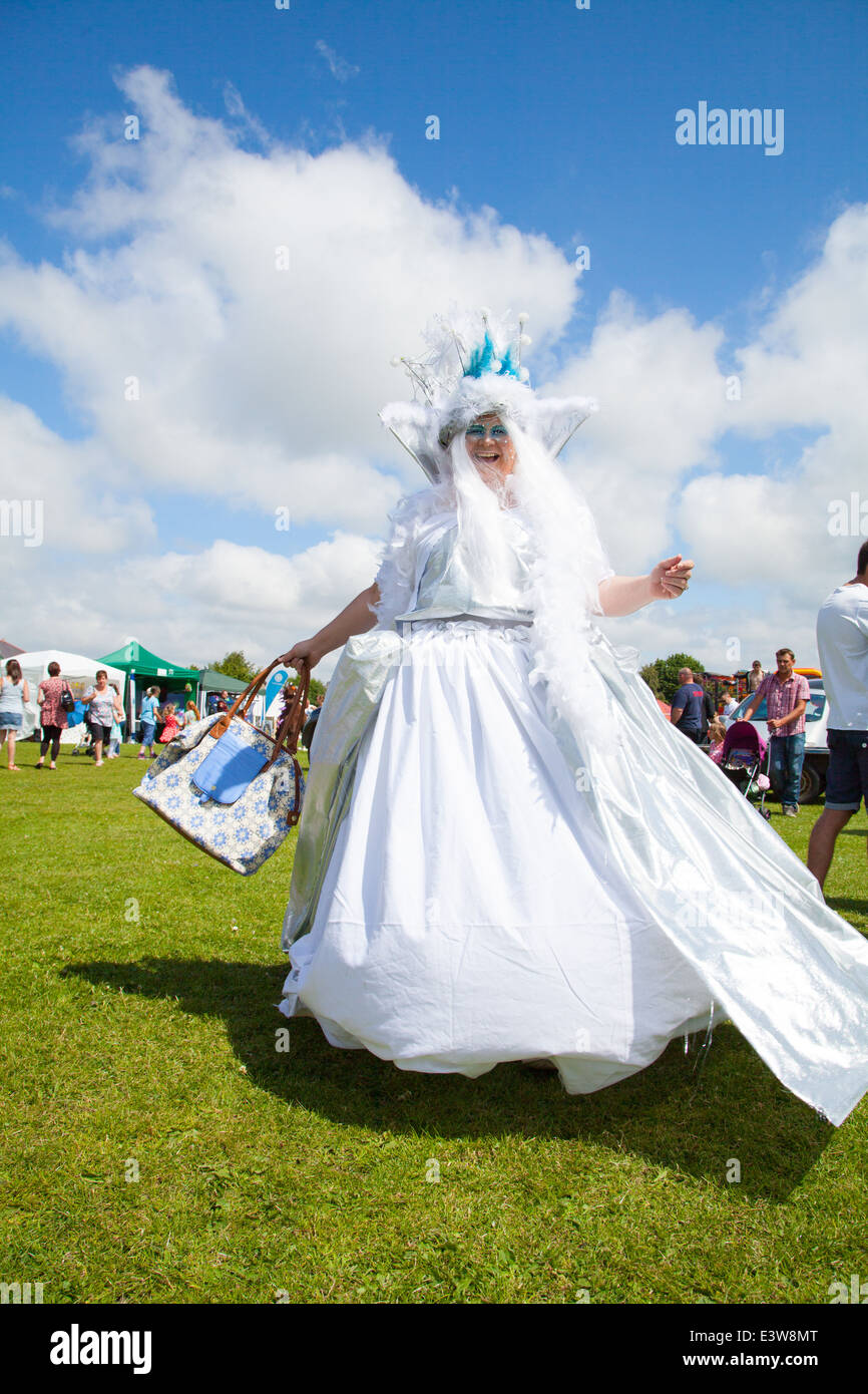 Une femme vêtue comme une bonne fée en robe de satin blanc virevoltant et rire à huis clos à Denbigh ville carnaval d'été Banque D'Images