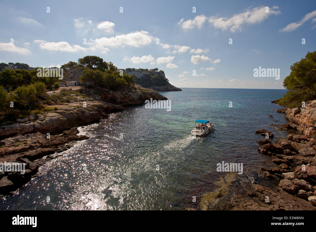 Sortir - parti des gens sur un bateau à moteur en laissant Cala Galdana. Banque D'Images