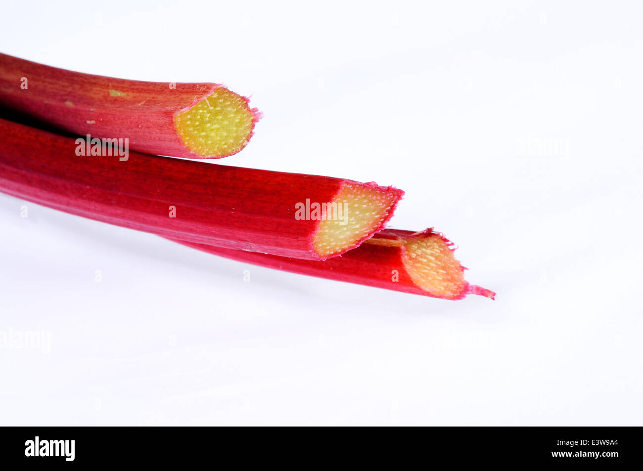 Trois bâtons de rhubarbe contre un arrière-plan. Banque D'Images