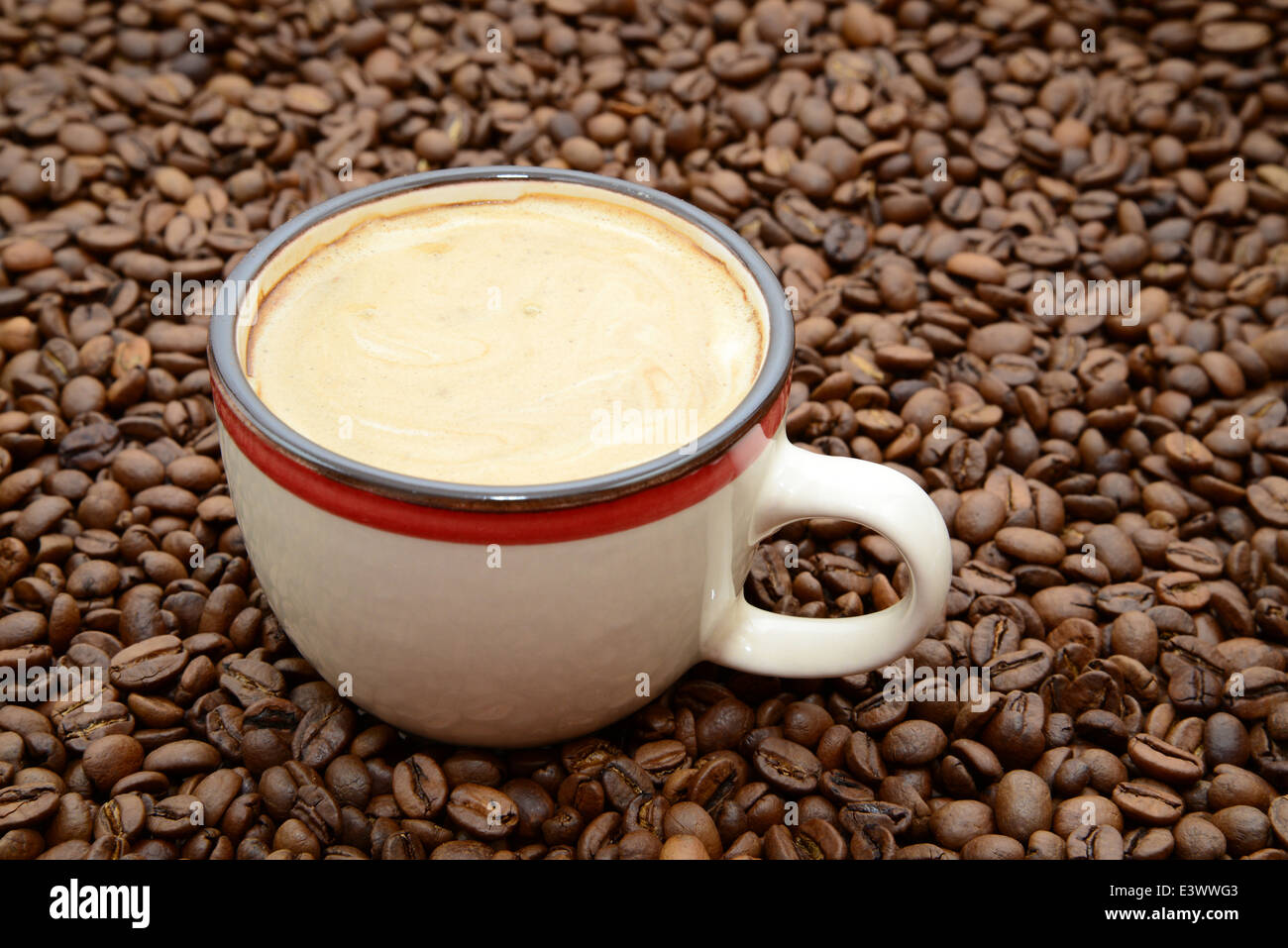 Tasse de café avec de la crème sur un fond de grains de café Banque D'Images