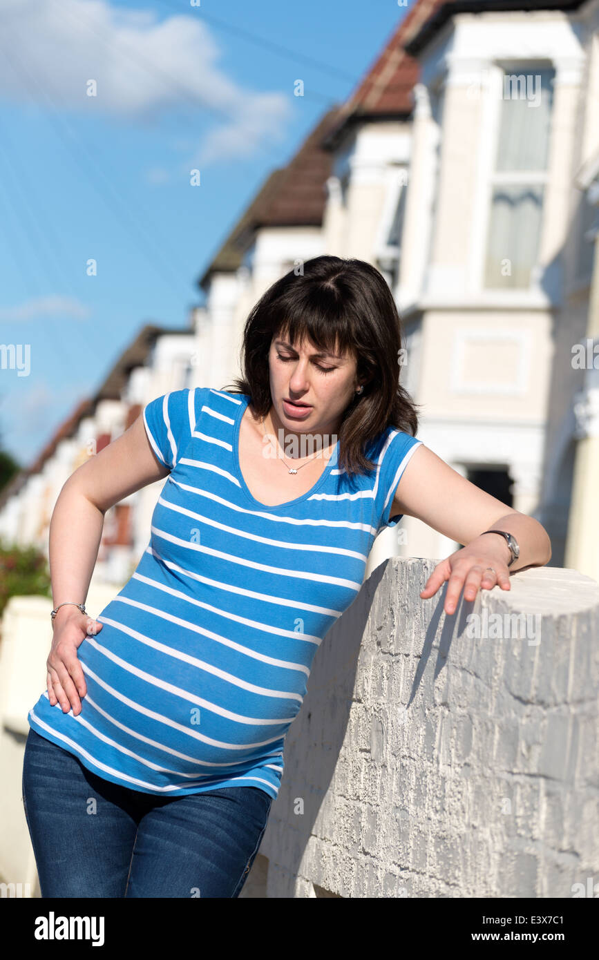 Femme enceinte prendre du repos pendant les contractions dans la rue, England, UK Banque D'Images