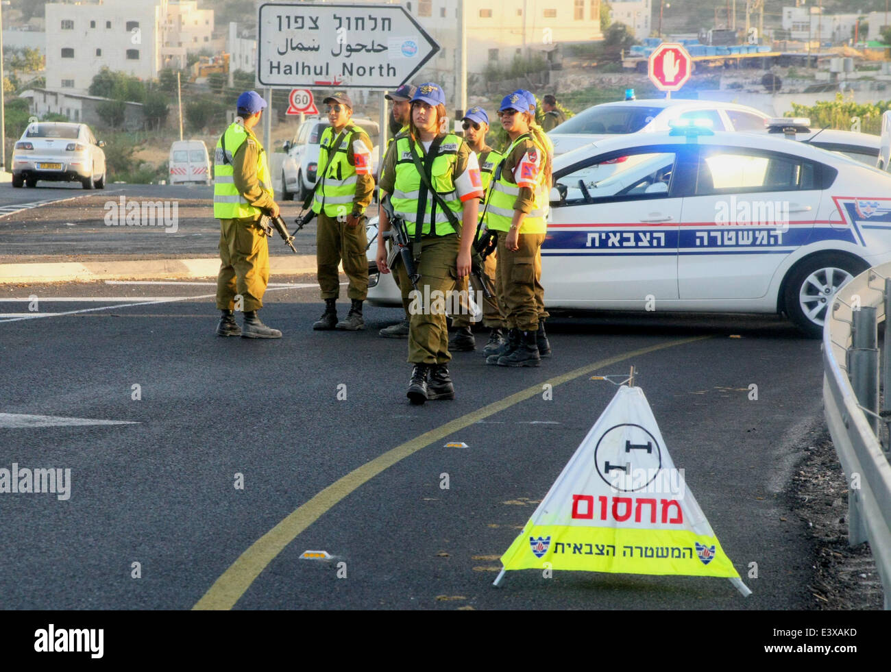 30 juin 2014 - Hébron, en Cisjordanie, territoire palestinien - membres des forces de sécurité israéliennes se tiennent près de leurs véhicules comme ils bloquent l'entrée nord d'Halhul, village, près de la ville de Cisjordanie d'Hébron, le 30 juin 2014. Plus tôt lundi, les corps des trois qui avaient été kidnappés israéliens enlevés il y a deux semaines, plus de ont été découverts par les forces de sécurité juste au nord d'Hébron. Et après la découverte des trois instances israéliennes, les militaires israéliens ont bloqué toutes les entrées à Hébron (crédit Image : © Mamoun Wazwaz APA/Images/ZUMAPRESS.com) Banque D'Images