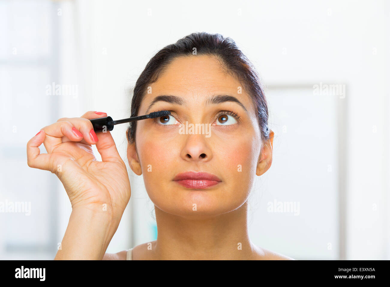 Mixed Race woman applying makeup Banque D'Images