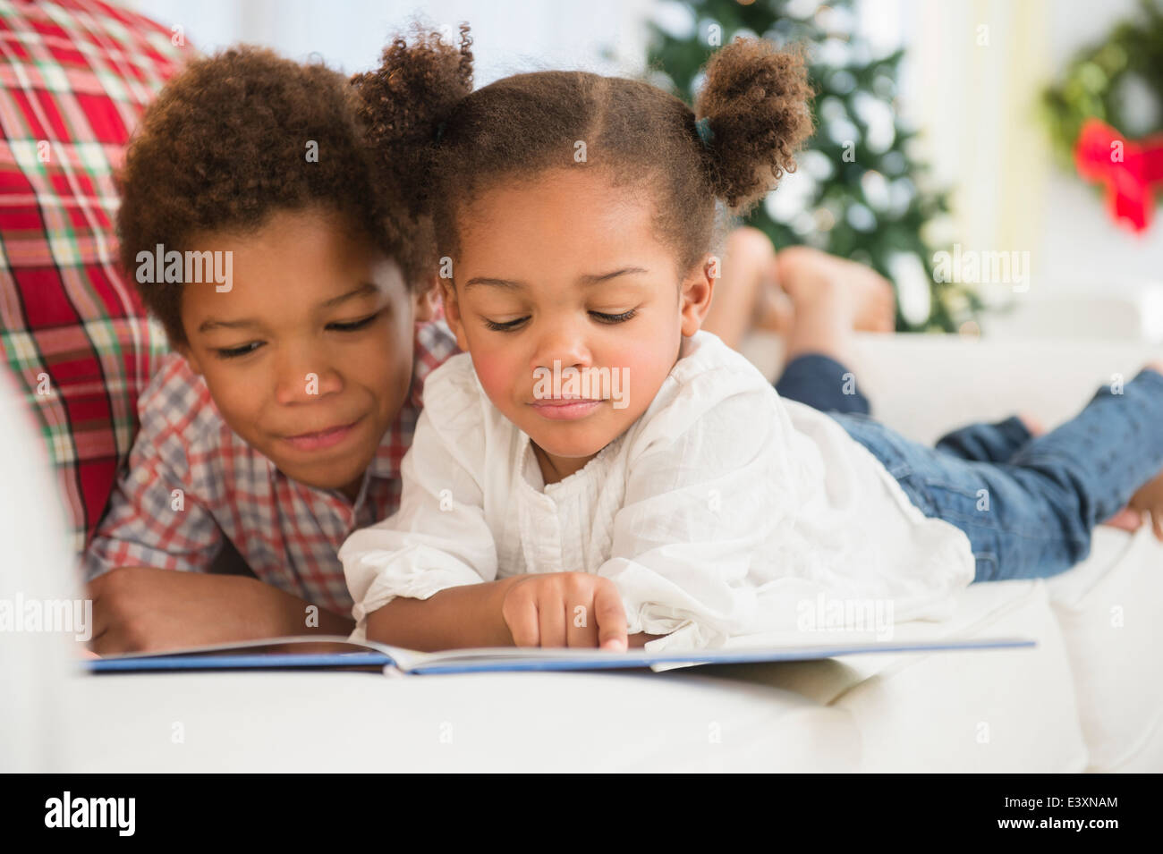 Les enfants noirs lire ensemble sur canapé Banque D'Images