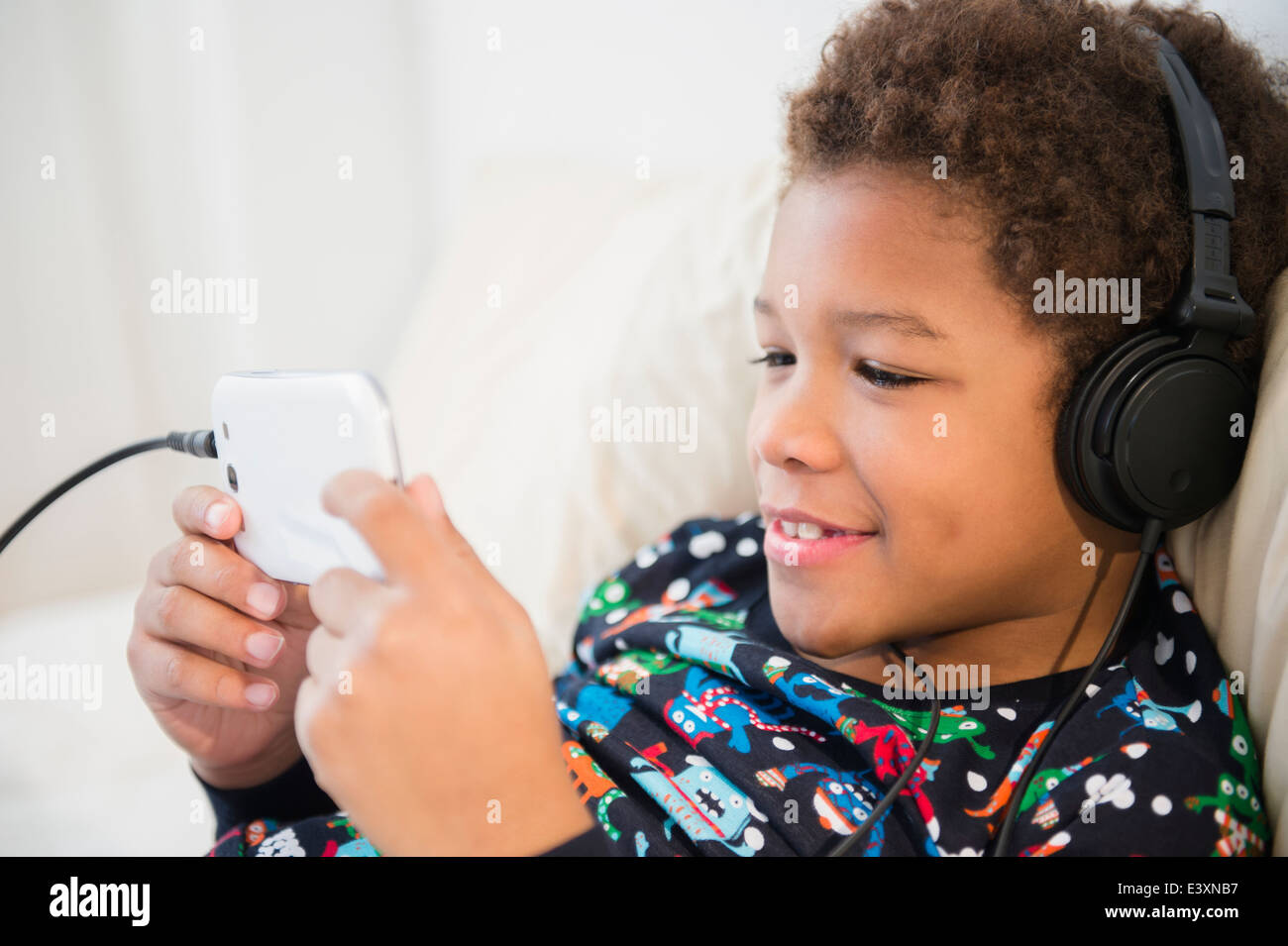 Black Boy listening to headphones on sofa Banque D'Images