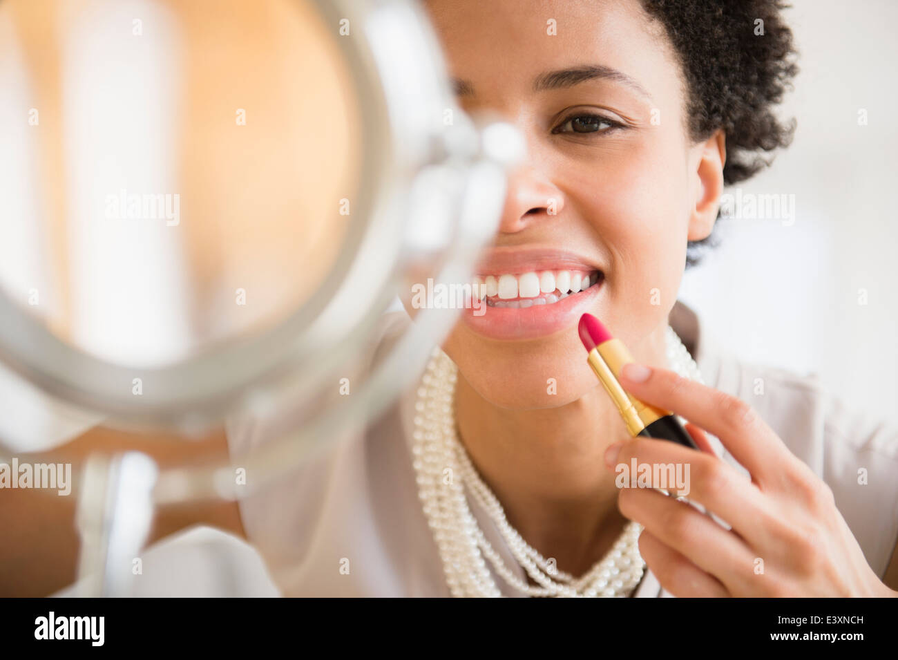Black woman applying makeup in mirror Banque D'Images