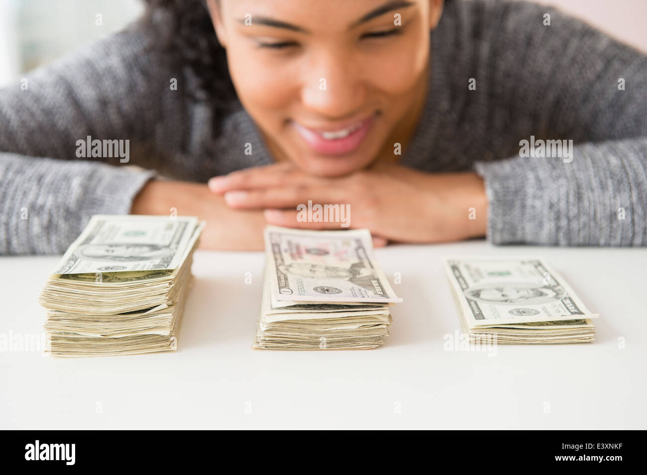 Mixed Race woman comptant des piles de l'argent Banque D'Images