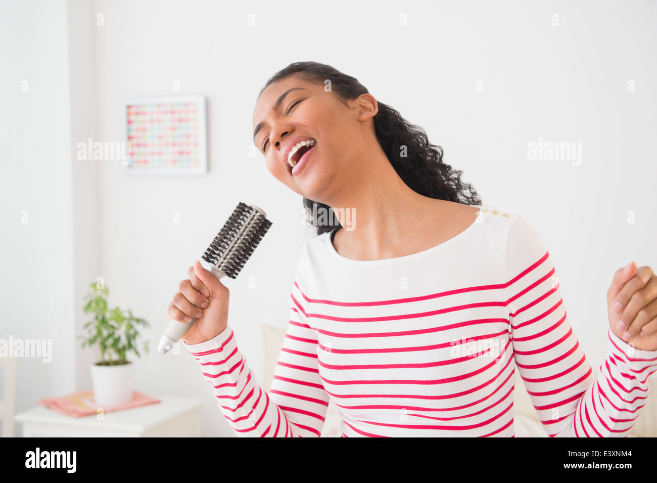 Mixed Race woman singing into hairbrush Banque D'Images