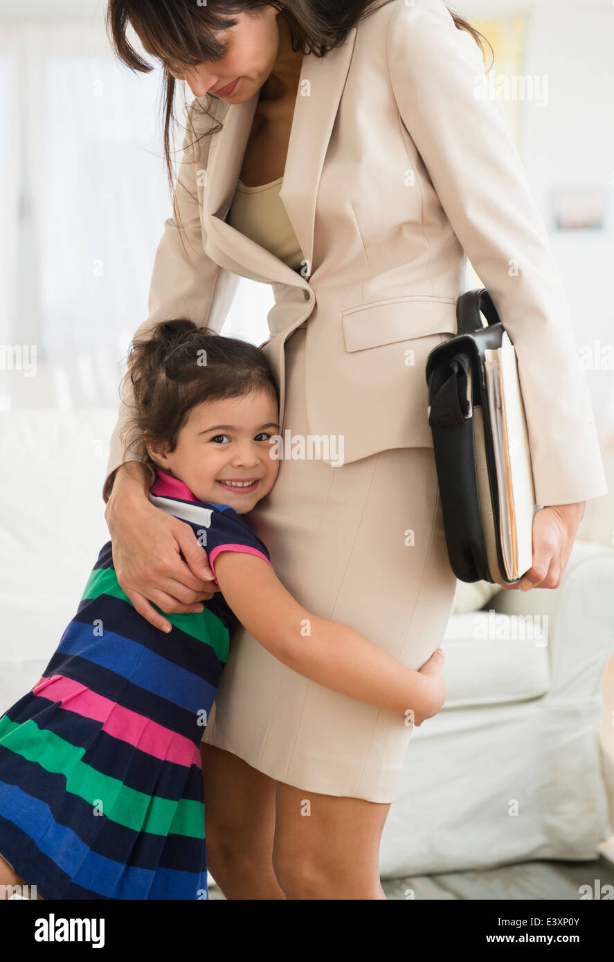 Young daughter hugging mère alors qu'elle quitte pour le travail Banque D'Images