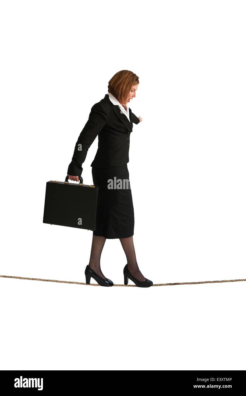 Businesswoman walking sur un fil ou highwire isolé sur fond blanc Banque D'Images