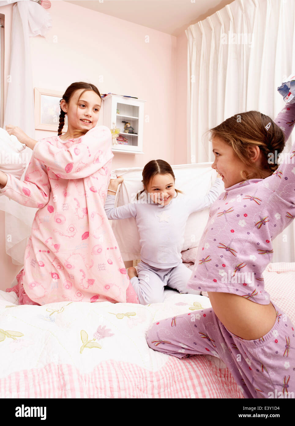 Mixed Race girls having pillow fight on bed Banque D'Images