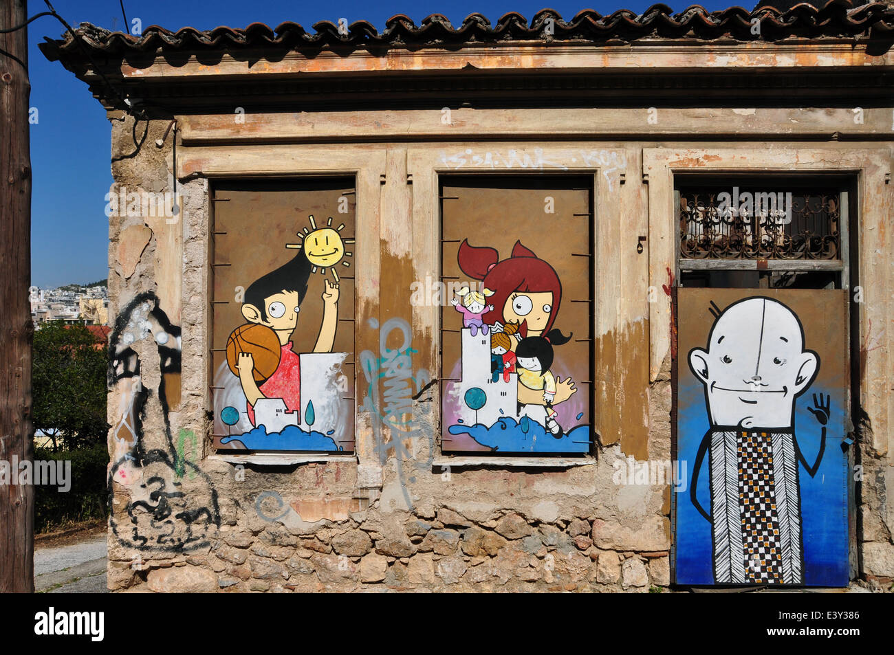 Graffitis colorés joyeux personnages de dessins animés sur la barricadèrent les fenêtres et porte d'une maison abandonnée à Plaka. Banque D'Images