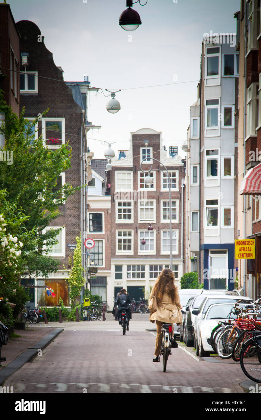 Un vélo de fille vélo à travers le quartier Jordaan à Amsterdam aux Pays-Bas Banque D'Images