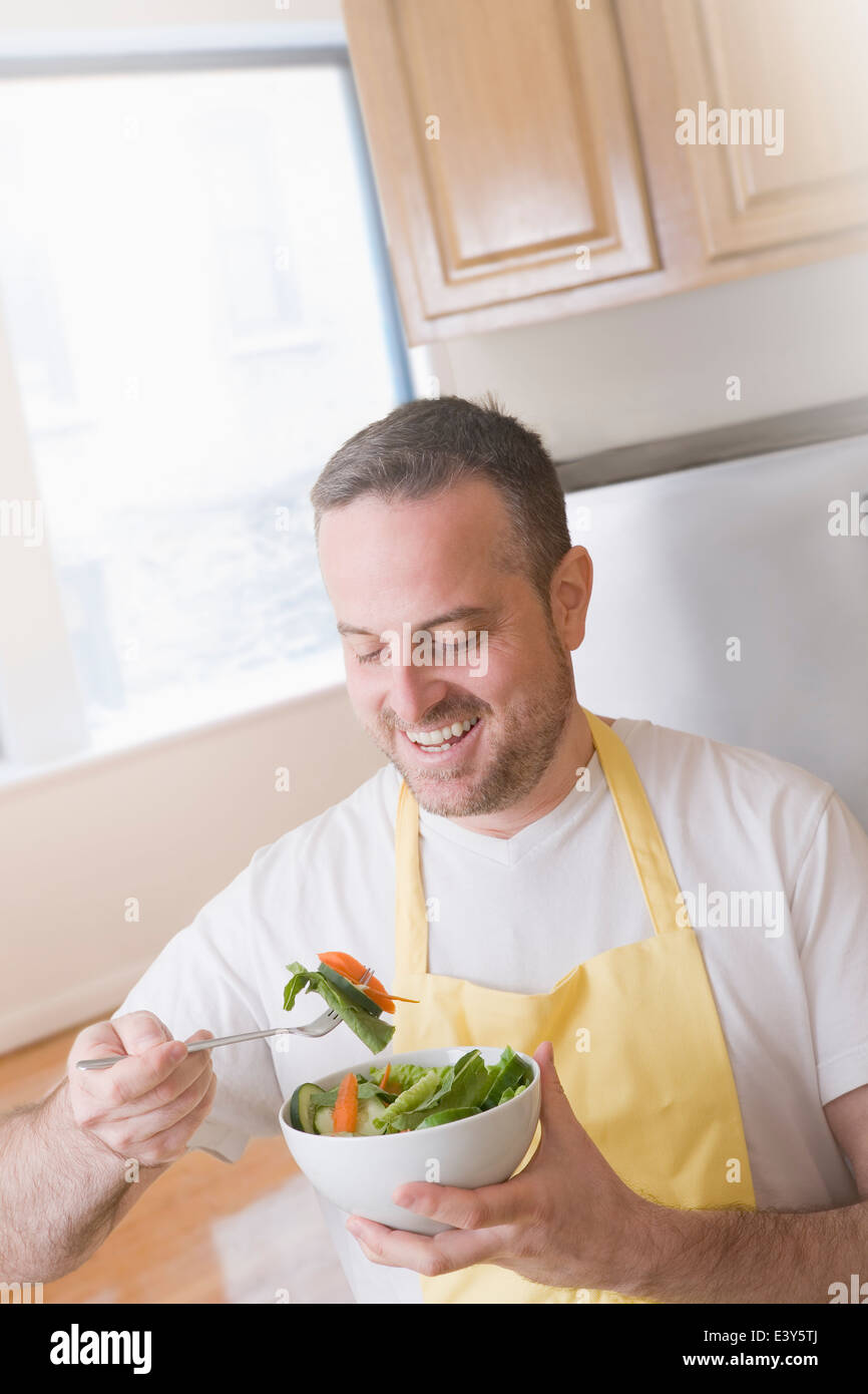 Homme mûr de manger un bol de salade fraîche dans la cuisine Banque D'Images